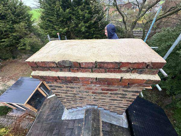 The stack capped off in fresh mortar, shaped to shed water