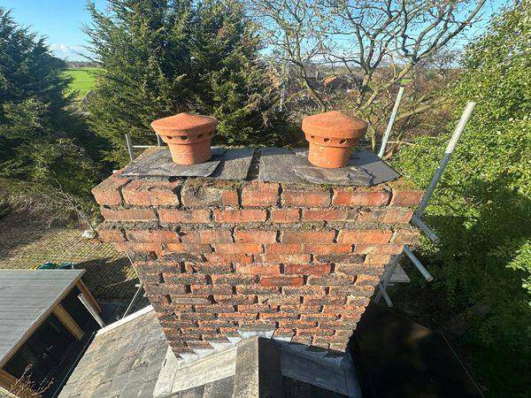 Weathered brickwork and eroded joints on the stack, pots and cowls above