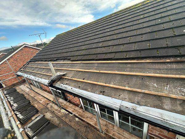 A course lifted at the eaves showing the torn old felt underneath