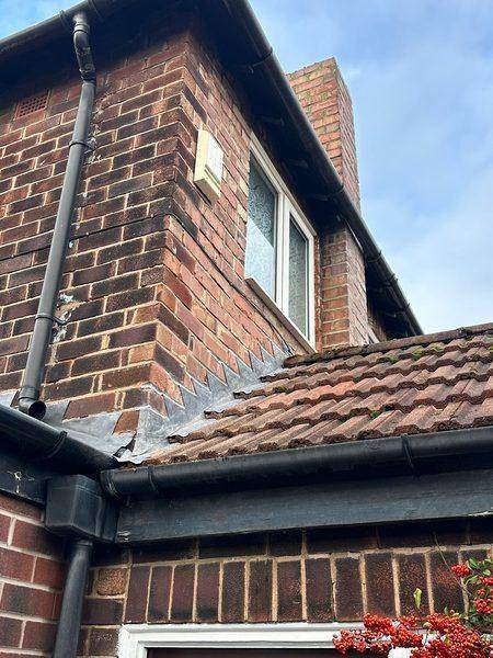 Where the low roof meets the house wall, with the old lead at the junction